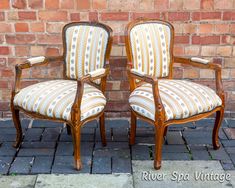 two chairs sitting next to each other in front of a brick wall