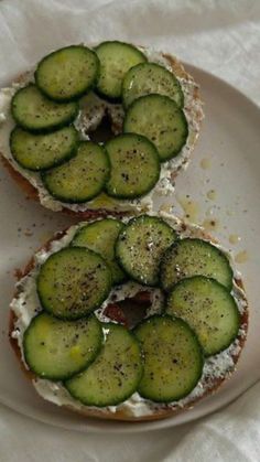 two pieces of bread with cucumbers on them are sitting on a white plate