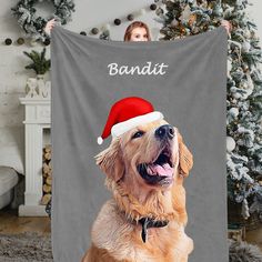 a golden retriever dog wearing a santa hat while sitting in front of a christmas tree