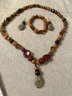 Long Orange and Brown Acrylic/Faux Wood Beaded Necklace with Pendant. Necklace comes with matching bracelet and earrings. Beads are round and elongated in shape. Necklace is on Elastic Cord. Brown Beaded Necklace, Brown Acrylic, Earrings Beads, Necklace With Pendant, Orange Wood, Brown Jewelry, Wood Bead Necklace, Wood Necklace, Matching Bracelet