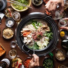 many people are eating and drinking at a table full of food, including salads