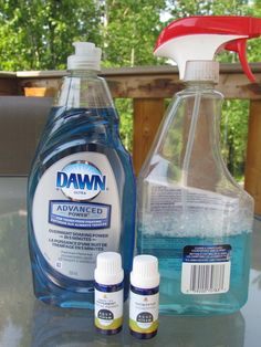 two bottles of dawn advanced and one bottle of mouthwash on a table with trees in the background