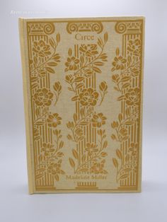 the front cover of an old book with flowers and leaves in gold on white background