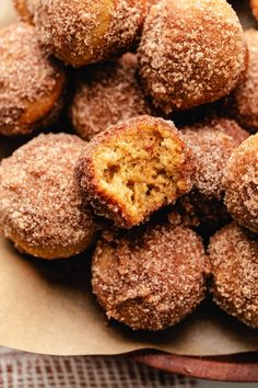 some sugared donuts are in a bowl on top of a cloth tablecloth