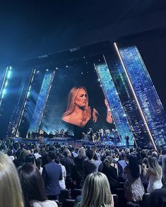 a woman standing on top of a stage in front of a large group of people