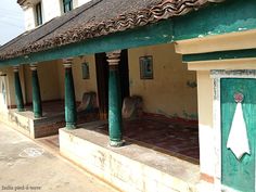 the outside of a building with green and white columns