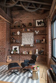 a living room filled with furniture and a brick wall mounted book shelf next to a window