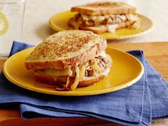 two plates with sandwiches on them sitting on a table