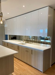 an empty kitchen with white cabinets and wood flooring is pictured in this image, there are lights hanging from the ceiling