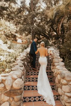 the bride and groom are walking up some stairs in their wedding dress, which is adorned with stones