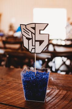 a cup filled with blue rice sitting on top of a wooden table next to a sign