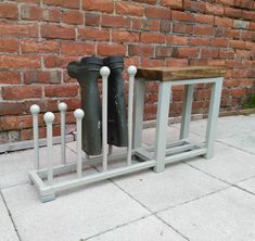 two black boots sitting on top of a metal stand next to a brick wall with white posts