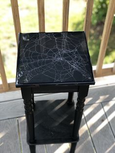 a black table with a spider web pattern on it's top sitting on a porch