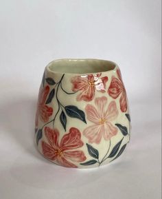 a vase with flowers painted on it sitting on a white tableclothed surface, ready to be used as a planter