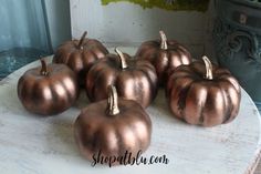 small copper pumpkins sitting on top of a white table