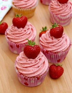 cupcakes with pink frosting and fresh strawberries on top are shown here