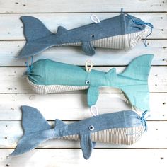 three stuffed sharks sitting on top of a white wooden floor next to each other and tied together