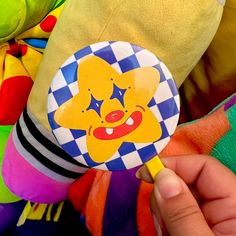 a hand is holding a colorful toy with a smiley face on it