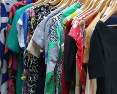 many different colored shirts are hanging on the clothes rack and there is no image here to provide a caption for