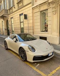 a white sports car parked on the side of the road in front of a building