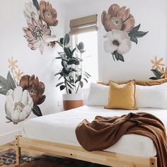 a white bed sitting in a bedroom next to a potted plant on top of a wooden frame