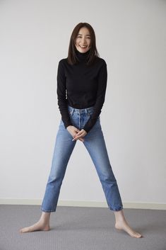 a woman in black shirt and jeans posing for the camera with her hands on her hips