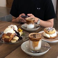 a man sitting at a table with two cups of coffee and pastries