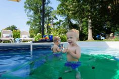 two young boys are playing in the pool