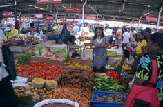 people shopping at an open air market with lots of fresh fruits and veggies