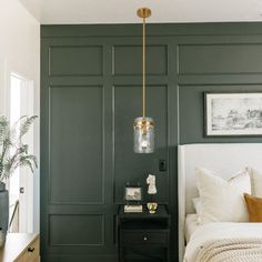 a bedroom with dark green walls and white bedding