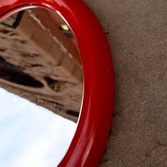 a red mirror sitting on top of a sandy beach