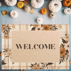 a welcome sign surrounded by pumpkins and gourds on a blue wooden background