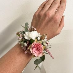 a woman's hand holding onto a pink and white flower wrist corsage