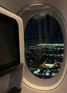 an airplane window looking out at the city lights