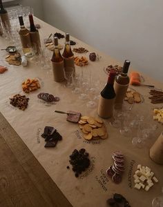 a table with wine bottles, crackers and other food items on top of it