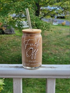 a glass jar filled with liquid sitting on top of a wooden table next to a tree