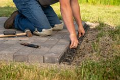 a man laying bricks on the ground with tools