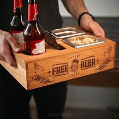 a man holding a wooden tray with two bottles of beer and a bowl of food