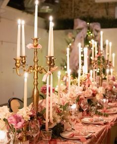 a long table with many candles and flowers on top of it, all set up for a formal dinner