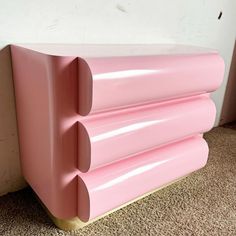 a pink cabinet sitting on top of a carpeted floor next to a white wall