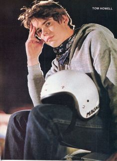 a young man sitting on top of a skateboard while talking on a cell phone