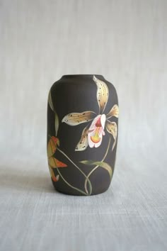 a black vase with flowers painted on it