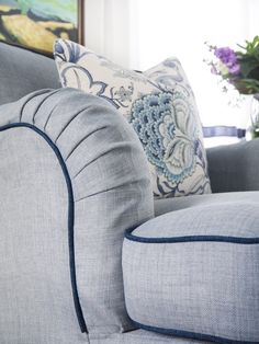 a gray couch with blue trim around the arms and pillows on it's back