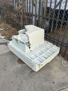 an old broken down laptop sitting on the ground in front of a fence and gate