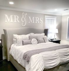 a large bed sitting in a bedroom under a mr and mrs decal on the wall