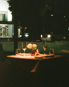 a table with wine glasses and candles on it in the middle of a street at night