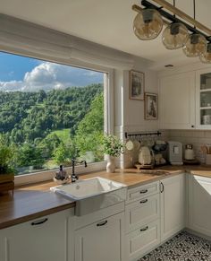 a kitchen with a large window looking out onto the valley below and trees in the distance