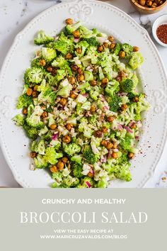 broccoli salad on a white plate with nuts and seasoning next to it