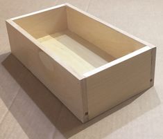 a wooden box sitting on top of a white tablecloth covered floor next to a wall