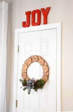 a white door with a christmas wreath and joy sign on it's front wall